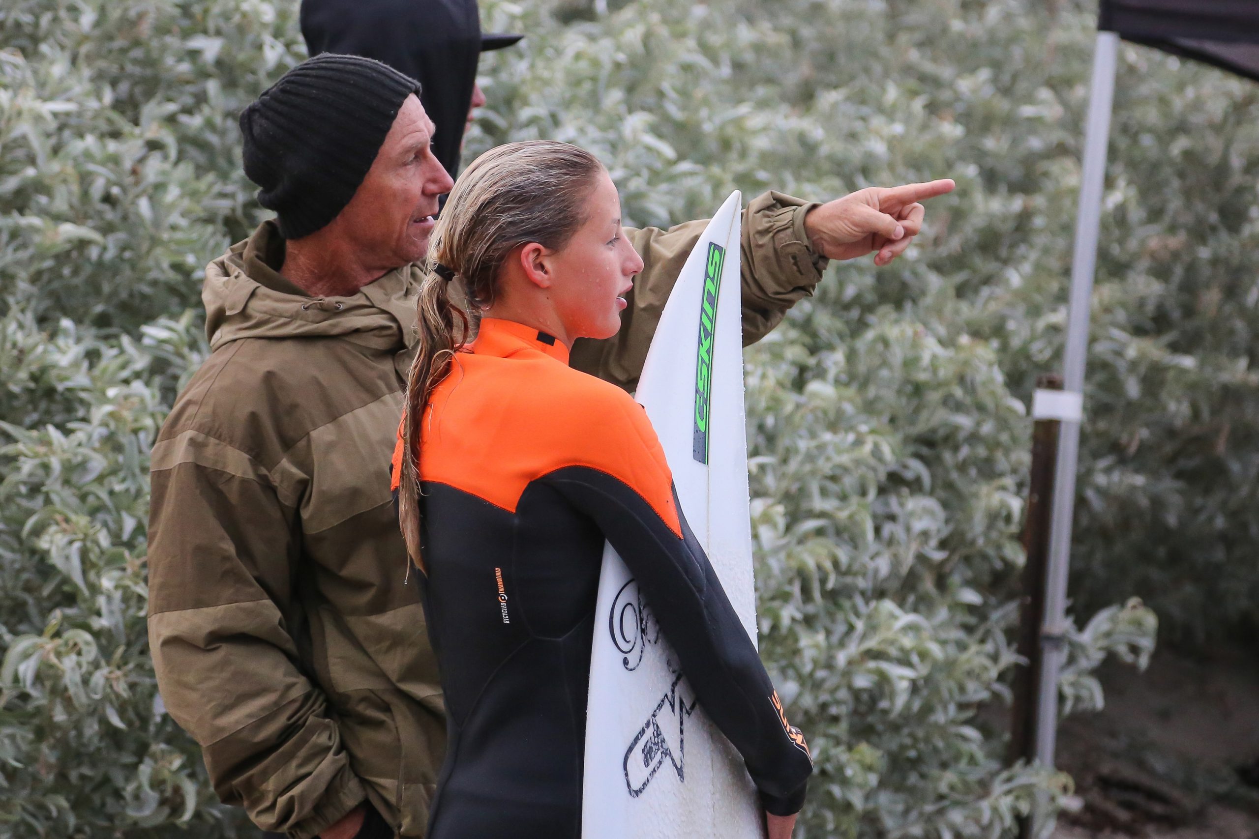 alt= Surf coach pointing and giving surfer advice