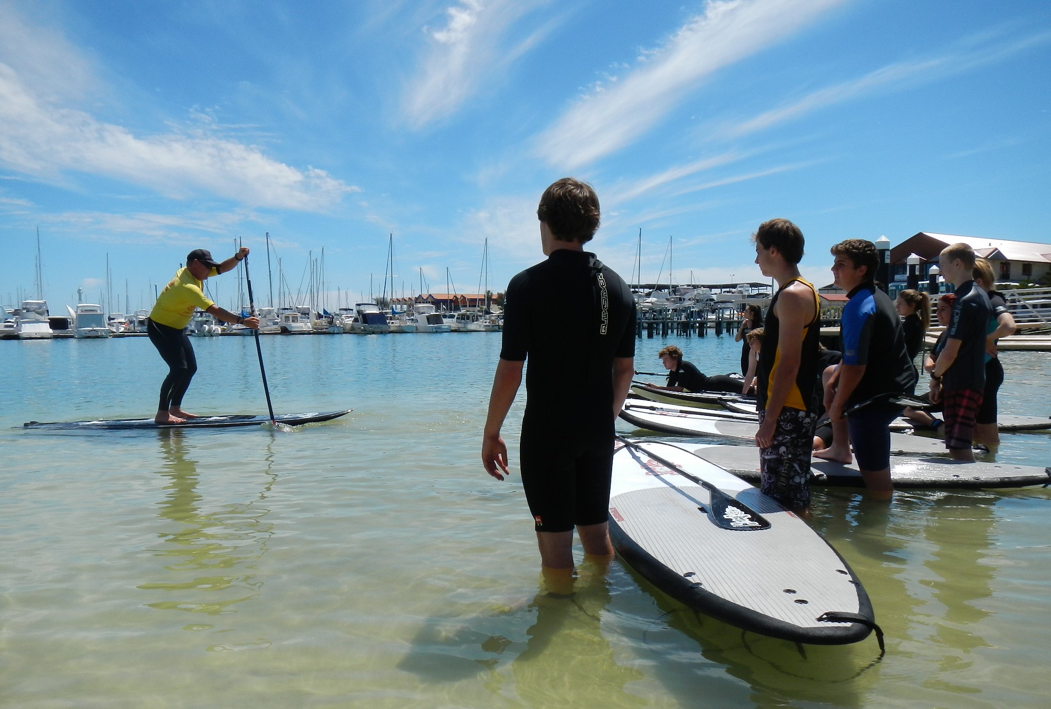 alt= Stand Up Paddle coach demonstrating paddling to students in Hillarys, Western Australia
